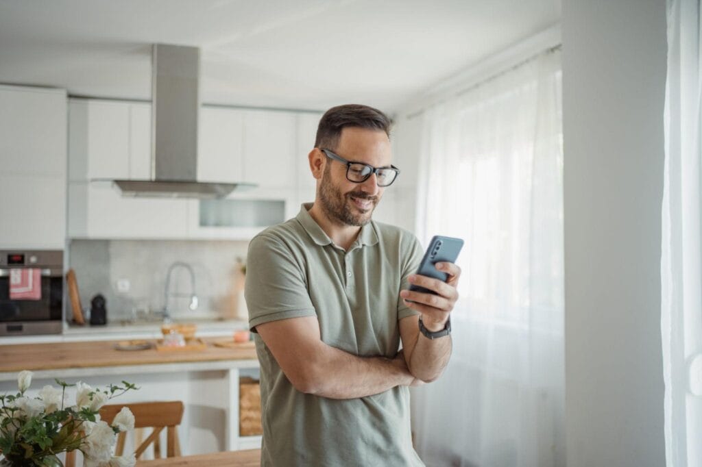 Man at home checking phone after reputation issue resolved
